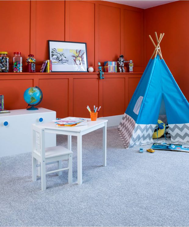 room with grey carpet and burnt orange walls, blue child's desk and teepee in corner